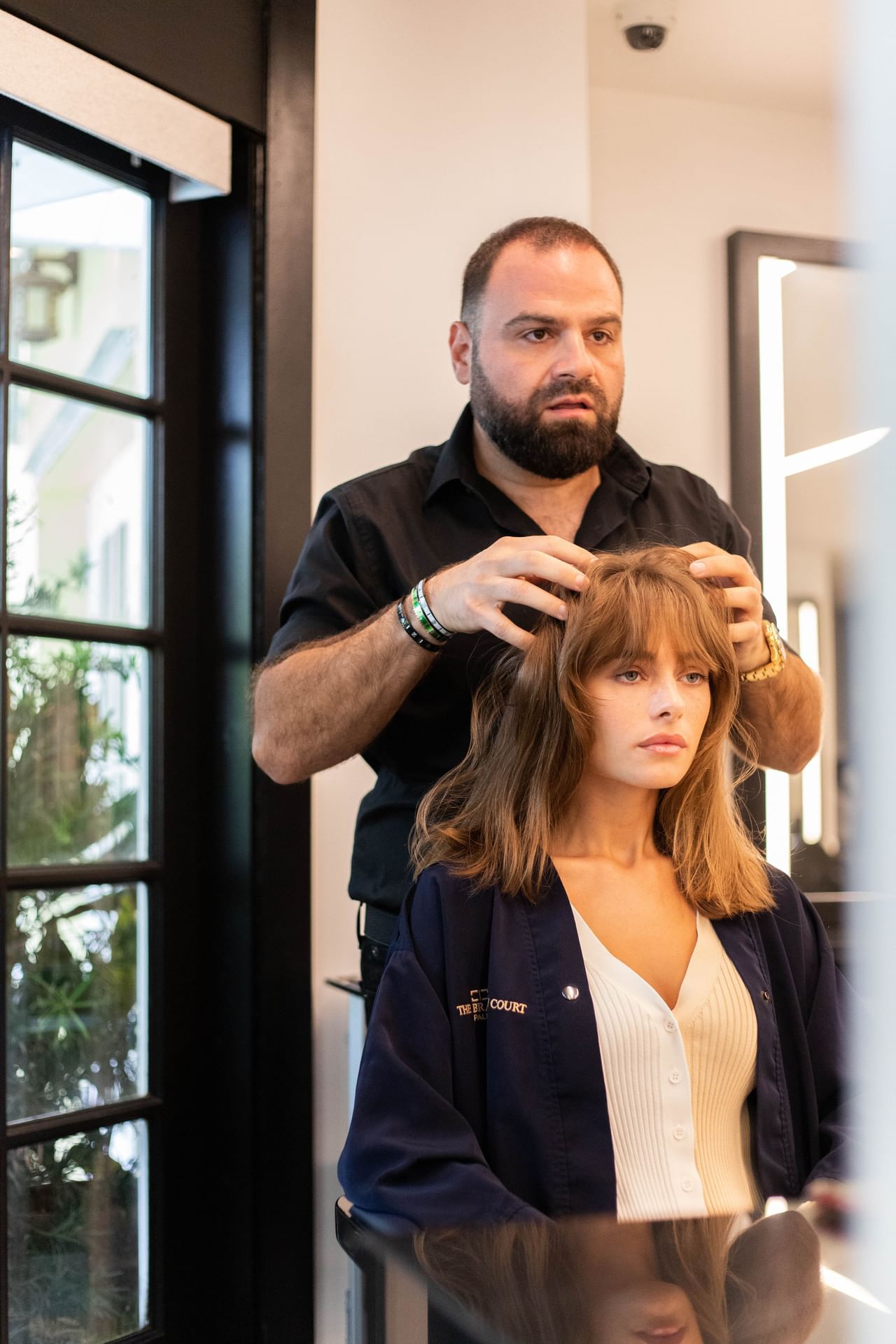 Male stylist styling the woman hair at Brazilian Court Salon